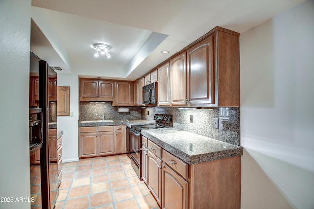 kitchen with light tile patterned floors, a sink, black appliances, a raised ceiling, and tasteful backsplash