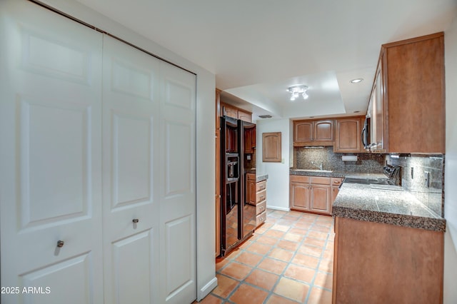 kitchen with electric stove, stainless steel microwave, tasteful backsplash, brown cabinetry, and light tile patterned floors