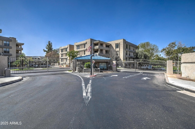 view of street with a gate, curbs, sidewalks, and a gated entry