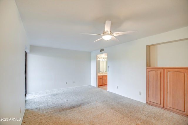 unfurnished bedroom featuring ensuite bath, a ceiling fan, visible vents, and carpet floors