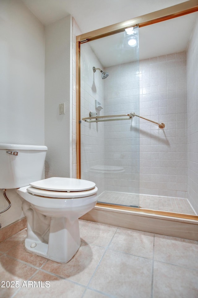 bathroom with tile patterned flooring, a shower stall, and toilet