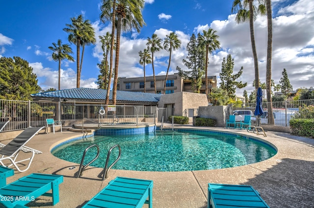 community pool with a patio area and fence