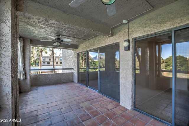 unfurnished sunroom with beamed ceiling and a ceiling fan