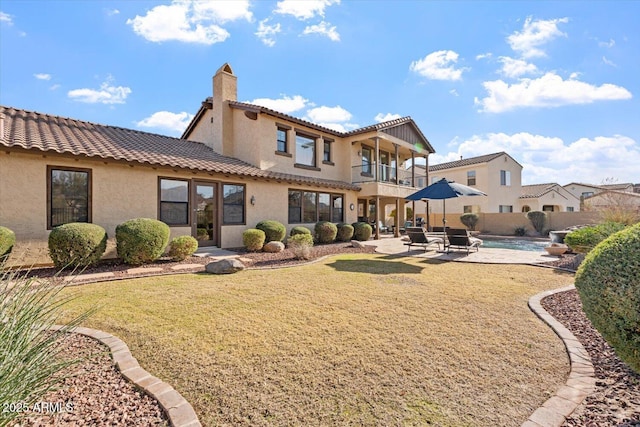 rear view of house with a patio area, a balcony, and a yard