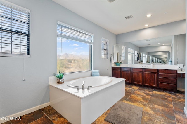 bathroom featuring a bathing tub, vanity, and a healthy amount of sunlight