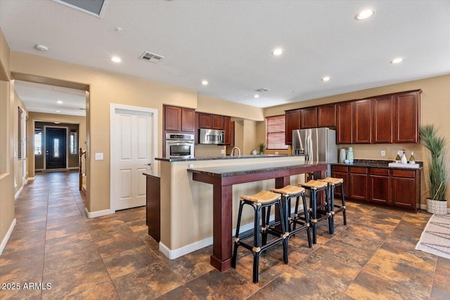 kitchen with a center island with sink, sink, a breakfast bar area, and appliances with stainless steel finishes