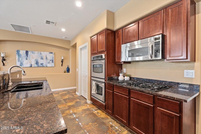 kitchen with dark stone countertops, sink, and stainless steel appliances