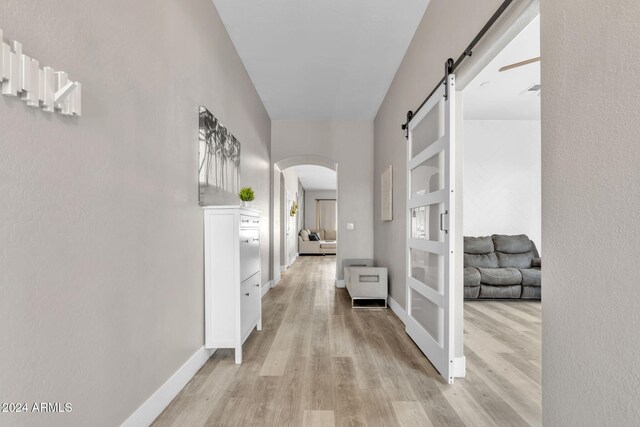 hallway with light wood-type flooring and a barn door