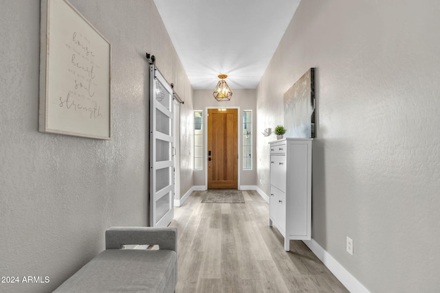 hall featuring a barn door and light hardwood / wood-style floors