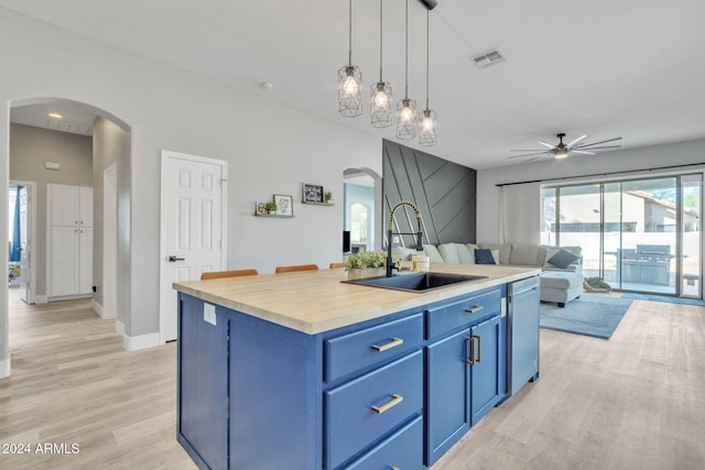 kitchen with ceiling fan, sink, blue cabinetry, pendant lighting, and a center island with sink