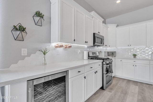 kitchen featuring white cabinets, decorative backsplash, stainless steel appliances, and wine cooler