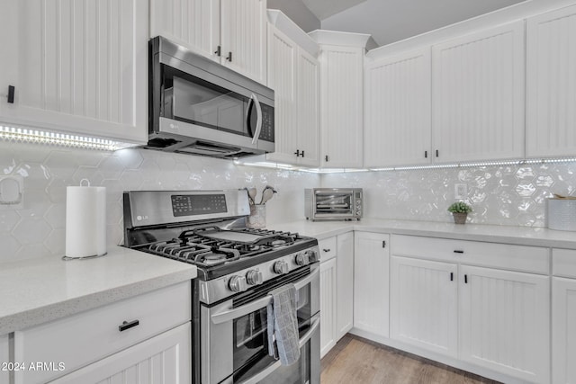 kitchen with tasteful backsplash, white cabinets, and appliances with stainless steel finishes