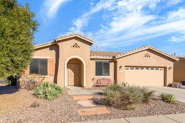 mediterranean / spanish-style house featuring stucco siding, an attached garage, a tile roof, and concrete driveway