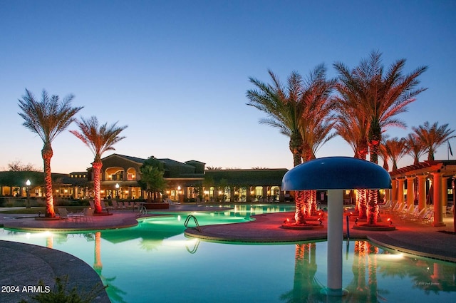 pool at dusk featuring a patio and a community pool