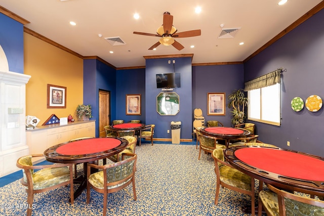 recreation room with a ceiling fan, ornamental molding, carpet, and visible vents