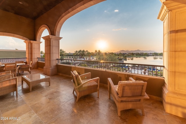 balcony at dusk featuring outdoor lounge area and a water view