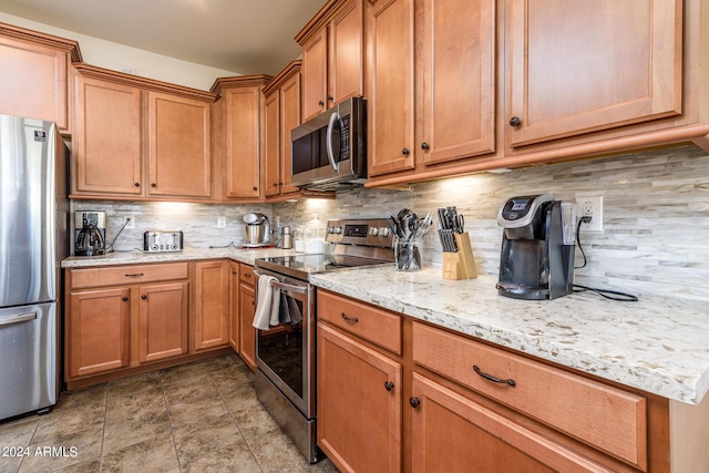 kitchen featuring brown cabinets, light stone countertops, decorative backsplash, and appliances with stainless steel finishes