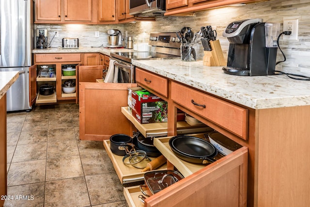 kitchen featuring backsplash, tile patterned flooring, stainless steel appliances, and brown cabinets