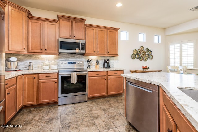 kitchen with visible vents, stainless steel appliances, brown cabinets, and tasteful backsplash