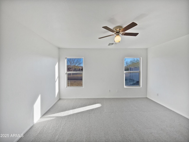 empty room featuring ceiling fan, carpet floors, visible vents, and baseboards