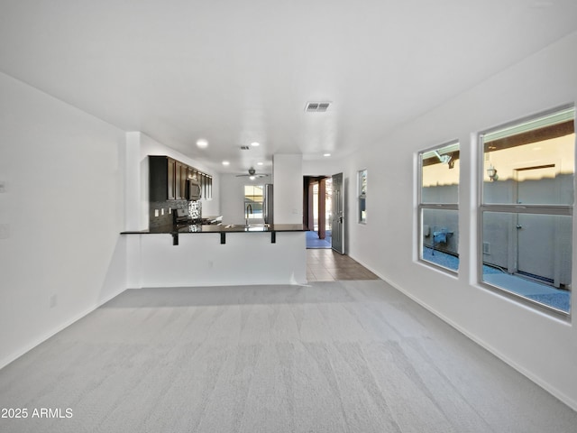 unfurnished living room featuring recessed lighting, light carpet, a ceiling fan, visible vents, and baseboards