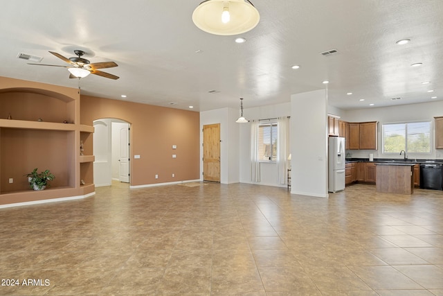 unfurnished living room with ceiling fan and built in features