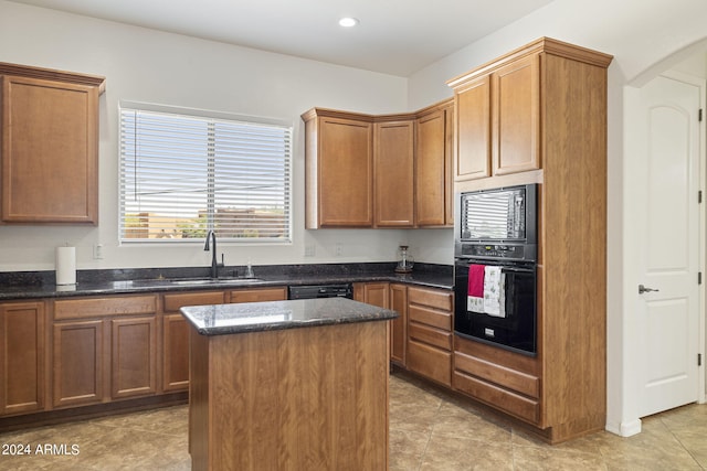 kitchen featuring dark stone counters, sink, a kitchen island, and black appliances