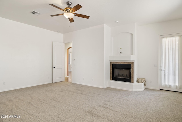 unfurnished living room with ceiling fan, light carpet, and a tile fireplace