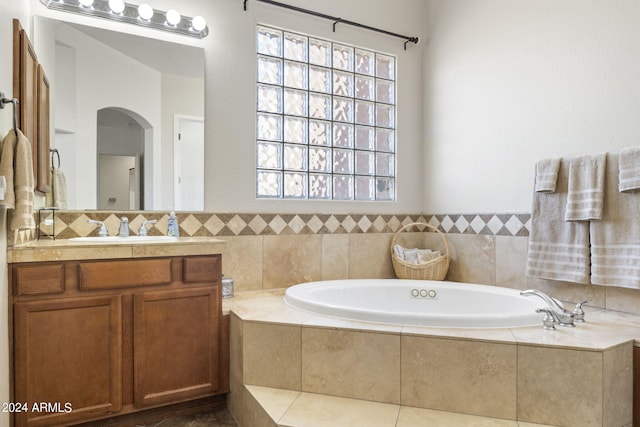 bathroom with vanity and a relaxing tiled tub