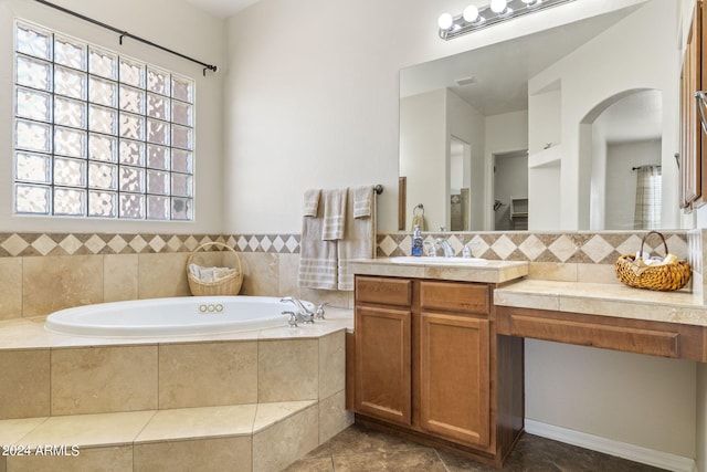 bathroom featuring tile patterned flooring, vanity, and tiled bath