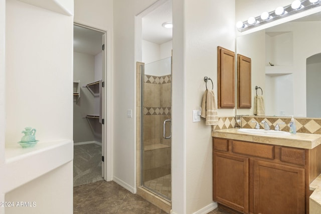 bathroom with vanity, tile patterned floors, a shower with shower door, and backsplash