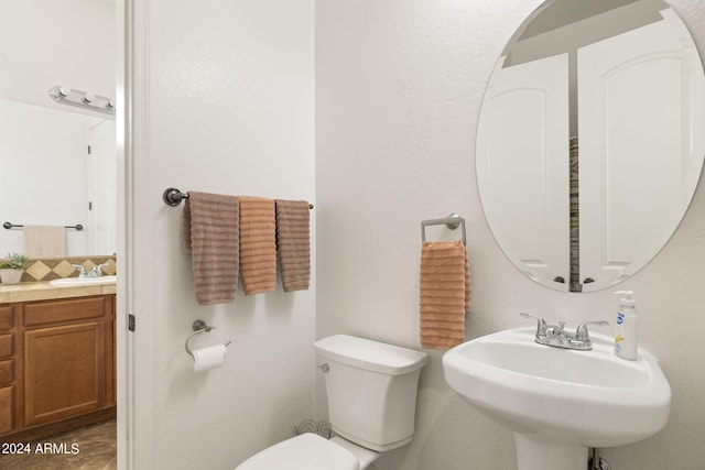 bathroom featuring backsplash, toilet, and sink