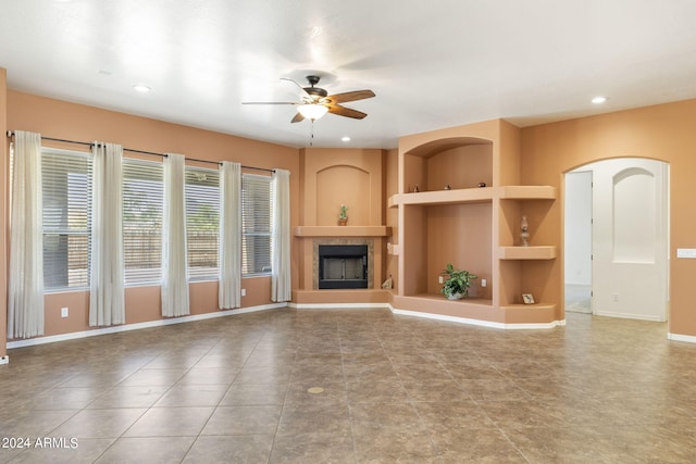 unfurnished living room featuring built in shelves and ceiling fan