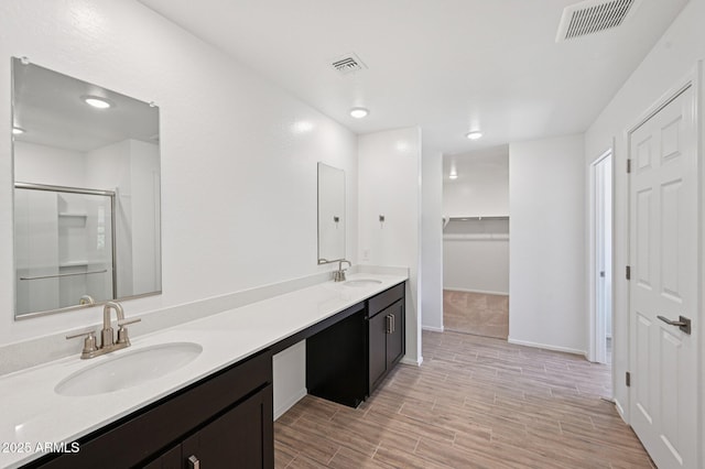 5535 S 240th Ln, Buckeye, AZ 85326 - bathroom with double vanity, a shower stall, a walk in closet, and wood finished floors