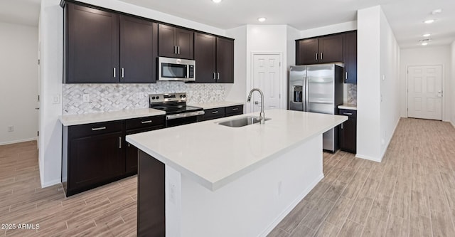 5535 S 240th Ln, Buckeye, AZ 85326 - kitchen with stainless steel appliances, light wood finished floors, decorative backsplash, light countertops, and a center island with sink