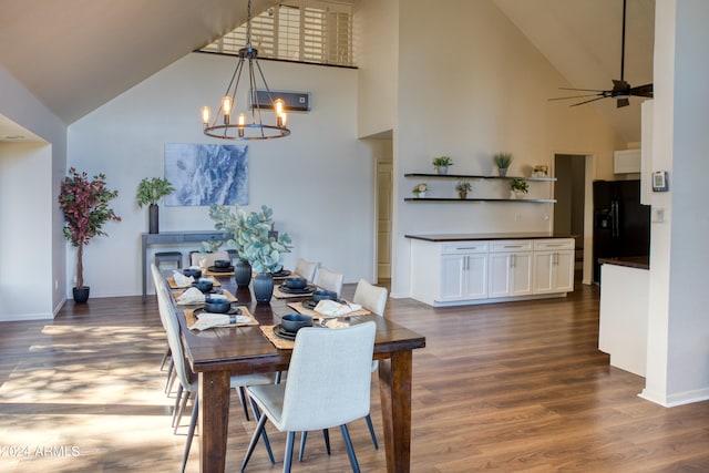 dining room featuring ceiling fan with notable chandelier, high vaulted ceiling, and dark hardwood / wood-style floors