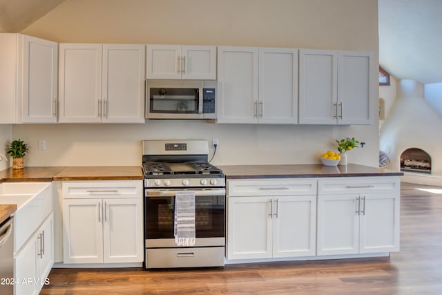 kitchen featuring light hardwood / wood-style floors, white cabinets, appliances with stainless steel finishes, and wood counters