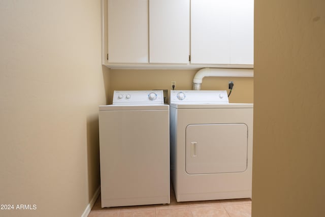 laundry area with light tile patterned floors, cabinets, and independent washer and dryer