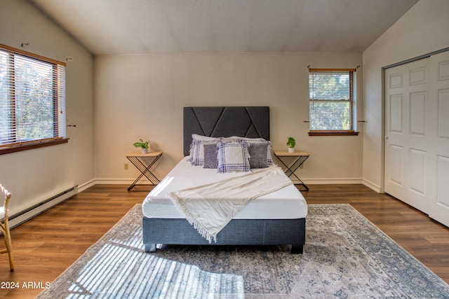 bedroom featuring lofted ceiling, a closet, a baseboard heating unit, and dark hardwood / wood-style flooring