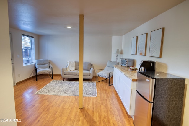 kitchen with white cabinets, light wood-type flooring, and stainless steel fridge