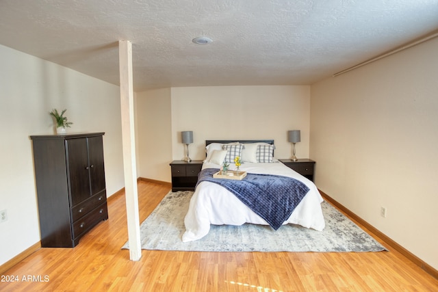 bedroom with light wood-type flooring and a textured ceiling