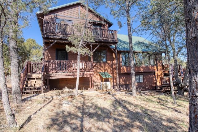 back of property featuring a balcony and a wooden deck