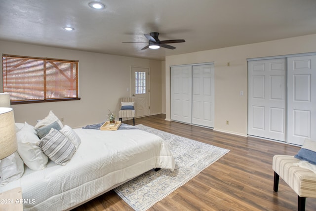 bedroom featuring ceiling fan, multiple closets, and dark hardwood / wood-style floors