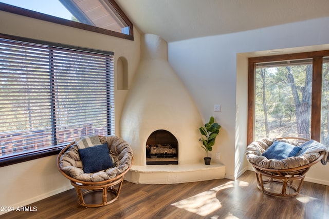 living area featuring vaulted ceiling, dark hardwood / wood-style flooring, and a large fireplace