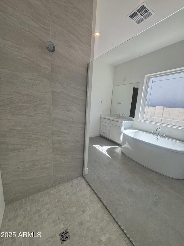bathroom with a freestanding tub, vanity, and tiled shower