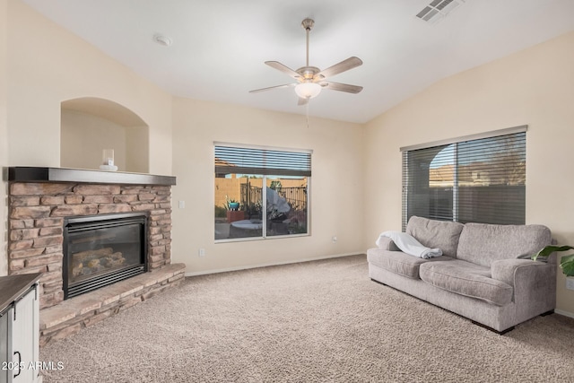 living room with ceiling fan, lofted ceiling, carpet flooring, and a stone fireplace