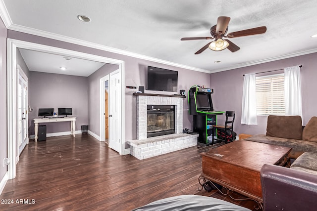 living room with ceiling fan, ornamental molding, a brick fireplace, and dark hardwood / wood-style floors