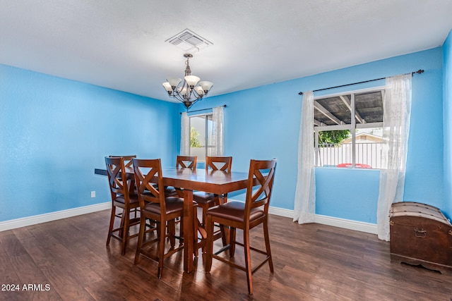 dining space with dark wood-type flooring, a notable chandelier, and a wealth of natural light