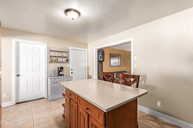 kitchen featuring a kitchen island, a textured ceiling, and light tile patterned floors