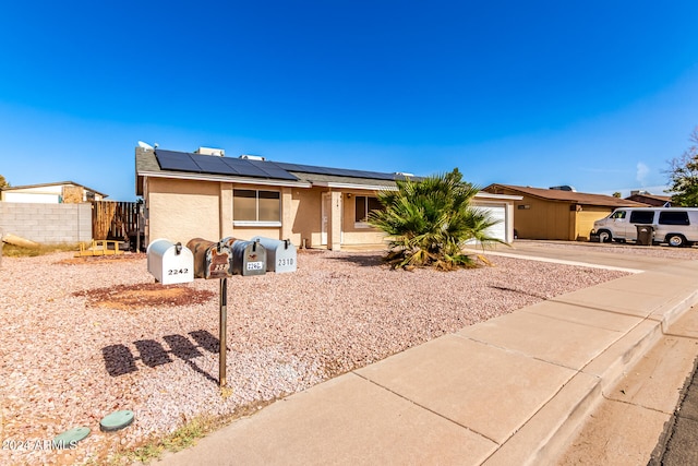 single story home with a garage and solar panels